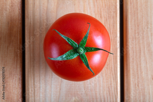 One red tomato on a wooden table, top view