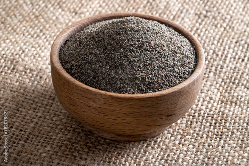 Ground black pepper in wooden bowl on burlap sack
