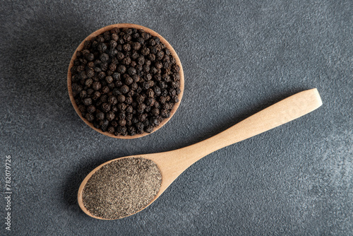 Ground black pepper with grains of black pepper on black background
