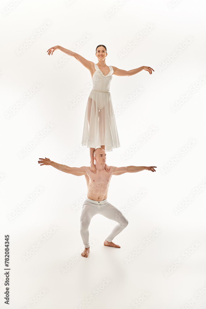 Shirtless young man and woman in a white dress gracefully dance, showcasing acrobatic balance.