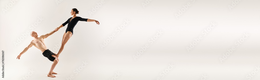 A shirtless young man and a young woman perform acrobatic elements in mid-air, showcasing a graceful and mesmerizing dance routine.