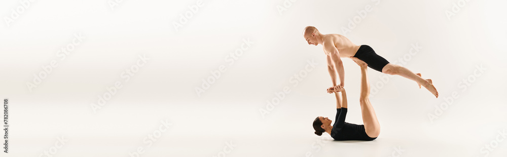 Shirtless young man and woman performing synchronized handstands in a studio setting against a white background. Shirtless young man and woman performing synchronized handstands in a studio setting against a white background.
