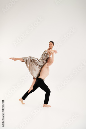 Shirtless young man and woman in shiny dress executing acrobatic dance moves on white background