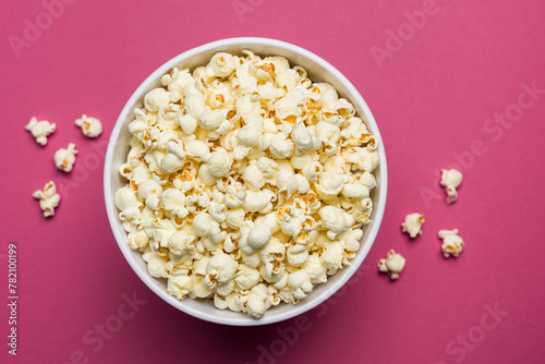 Salted popcorn in classic bucket on magenta background.