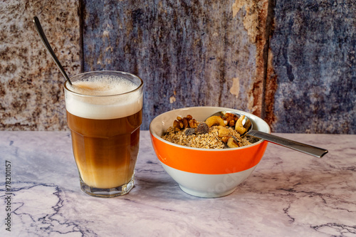 Morning meal with a bowl of oatmeal and nuts. Next to it is a glass of latte macchiato.