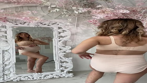 Beautiful pregnant woman in special beige pregnancy underwear. Advertisement of comfortable basic pregnancy underpants. Happy blond girl show her panties in room with flowers. Caucausian woman stand