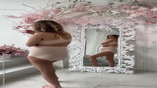 Beautiful pregnant woman in special beige pregnancy underwear. Advertisement of comfortable basic pregnancy underpants. Happy blond girl show her panties in room with flowers. Caucausian woman stand