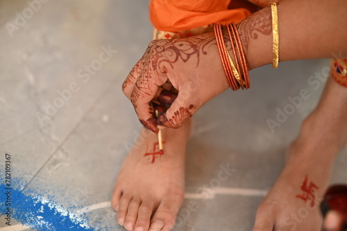 Applying Hindu Swastik on leg. a Swastik As Symbol Of Sun. Hindu Religion. Worship. Red ink. Woman indian hand drawing symbol