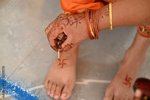 Applying Hindu Swastik on leg. a Swastik As Symbol Of Sun. Hindu Religion. Red ink. Woman indian hand drawing symbol