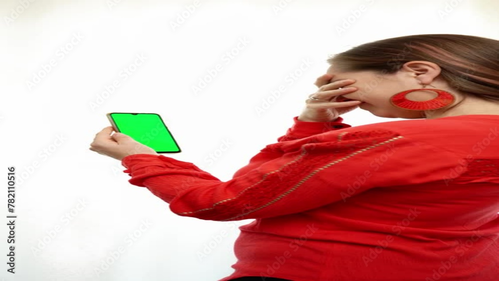 Young woman worried while looking at her cell phone. Young woman looking at her cell phone. Worried woman with a cell phone with green screen. Cell phone with green screen ready for advertising. Young woman worried while looking at her cell phone. Young woman looking at her cell phone. Worried woman with a cell phone with green screen. Cell phone with green screen ready for advertising.