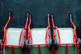 Array of red wheelbarrows lined up against a dark textured wall