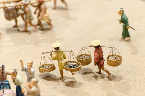 Photography A group of people are carrying baskets of fish on a beach