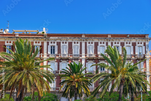 Cagliari waterfront historic buildings facade with wooden window shutters and iron balconies under clear blue sky in Sardinia Island, Italy.