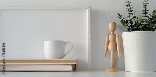 white frame background, a small wooden mannequin doll next to a stack of books and a coffee mug on a white table top