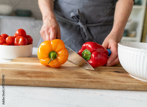 Quadro su tela Woman preparing bell peppers on a cutting board in the kitchen