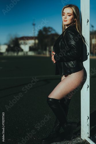 Sexy girl at the stadium in a bodysuit and leather jacket