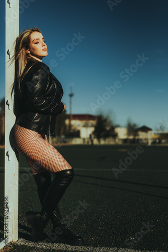 Sexy girl at the stadium in a bodysuit and leather jacket