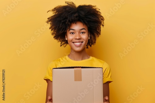 Beauty black woman with yellow t-shirt holding a cardboard box in a yellow background photo