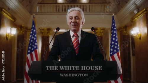 Positive President of the United States gives inspirational speech in the White House, then leaves. Senior US minister speaks at press campaign for media and television. American flags in background. photo