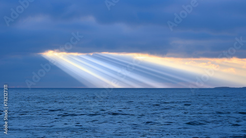 The sun is shining through the clouds, creating a beautiful rainbow in the sky. The ocean is calm and peaceful, with the sun reflecting off the water. The scene is serene and calming