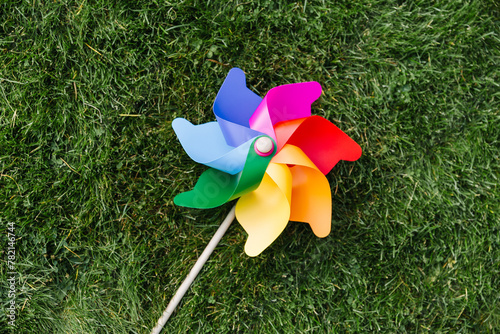ecology, environment and sustainable energy concept - close up of multicolored pinwheel on green lawn or grass © Syda Productions