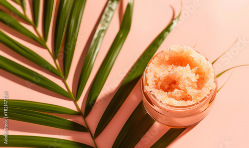 Skincare summer body scrub peeling product to nourish and hydrate dry flaky skin, lying on palm leaf pastel peach background.