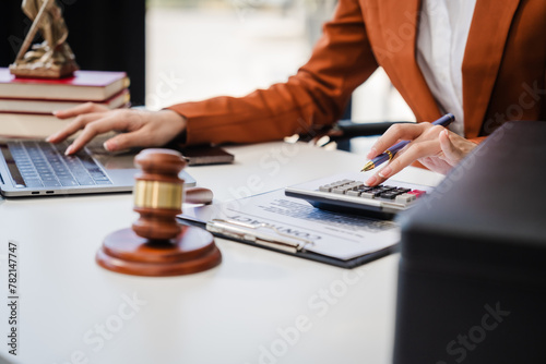 In Asian legal compliance, legal counseling office, a female lawyer reads a contract, advising on legal matters. clients, ensuring agreements align with laws and regulations, using calculator