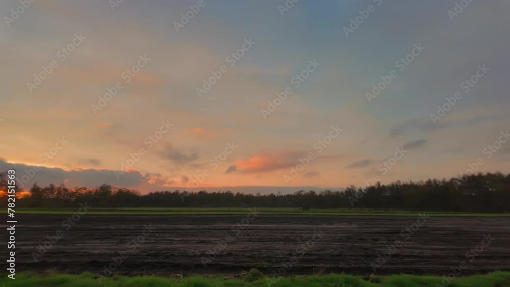 This video features a gentle panning view of a sunset over freshly plowed farmland. As the camera moves horizontally, the warm tones of the setting sun paint the sky with shades of orange and pink This video features a gentle panning view of a sunset over freshly plowed farmland. As the camera moves horizontally, the warm tones of the setting sun paint the sky with shades of orange and pink