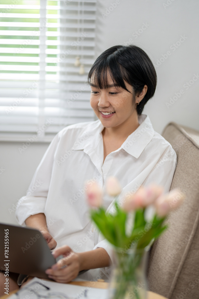 Relaxed young woman with a cheerful smile working on her laptop while comfortably sitting on a sofa at home. Relaxed young woman with a cheerful smile working on her laptop while comfortably sitting on a sofa at home.
