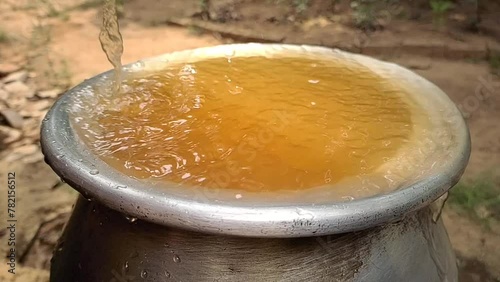 Bad, dirty, contaminated, impure, unhealthy, unhygienic, muddy and rusty brown colour drinking tap water overflowing from pot. Water shortage, scarcity crisis in india and africa rural village concept