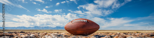 American Football on Rocky Terrain Against Blue Sky and Mountain Range