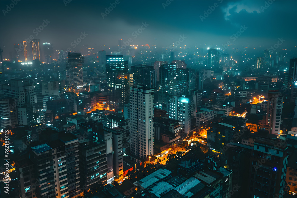 Aerial view of a cityscape at night with illuminated streets and buildings, showcasing the urban glow against a dark, moody sky.