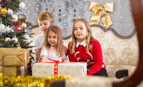 Two girls and boy on sofa in Christmas interior