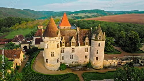 Cinematic stained glass castle with mullioned windows and rooms opening into the valley in France. Aerial view of Fortress at golden sunset in France, photo