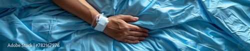 Patient's Hand with Hospital Bracelet on a Blue Hospital Bed Sheet