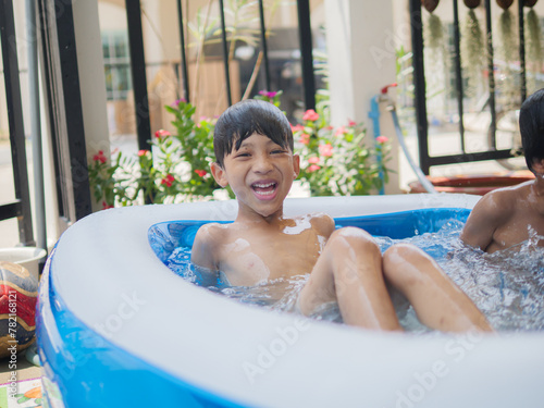 Two cute Asian children happily playing in an inflatable pool in summer. including jumping into the water, diving in the inflatable pond