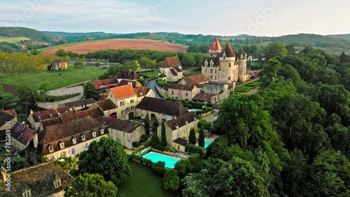 Cinematic stained glass castle with mullioned windows and rooms opening into the valley in France. Aerial view of Château des Milandes fortress at golden sunset in France, photo