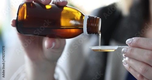 Woman pours cough syrup into measuring spoon. Medicines for lung disease concept