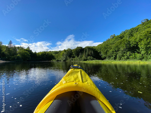 Yellow kayak on the lake. Inflatable kayak on a peaceful river in summer. Point a canoe surrounded by water, mountains and trees. Paddle on calm seas. © Stephanie