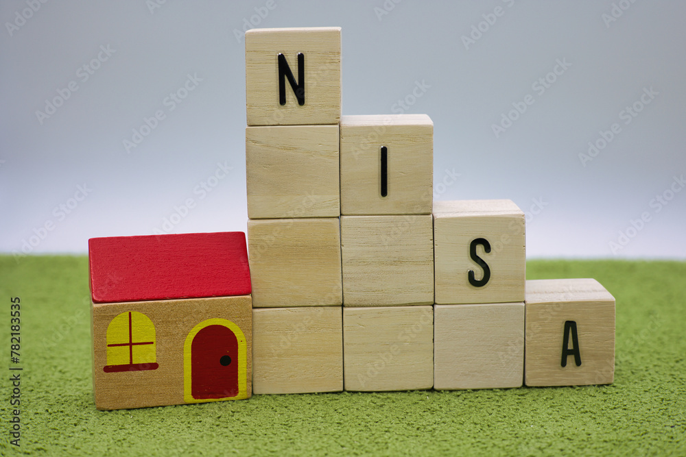 緑の絨毯に置かれたNISAの文字ブロック 緑の絨毯に置かれたNISAの文字ブロック