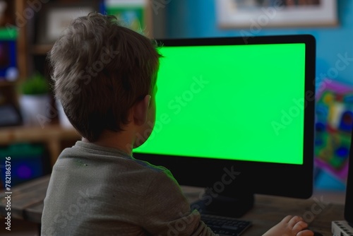 App preview over shoulder of a young boy in front of a computer with an entirely green screen