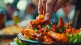 Hand reaching eagerly for a spicy Buffalo wing on a plate filled with flavorful food