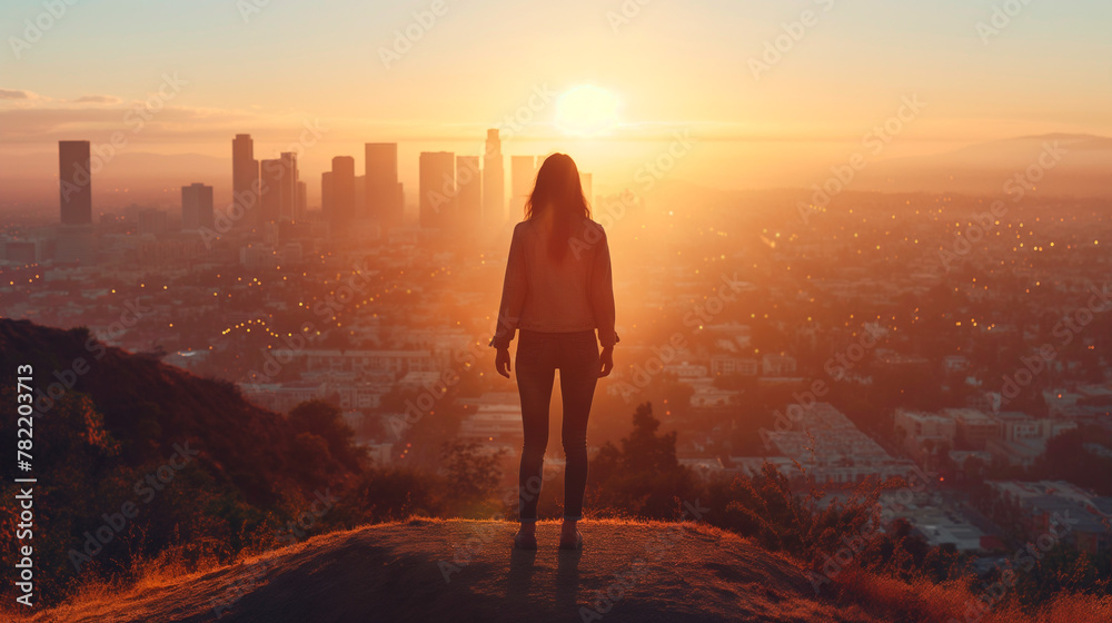 Fototapeta premium Silhouette of a woman overlooking city skyline at sunset. Concept of motivational articles, travel blogs, lifestyle magazines, and for promoting mental wellness