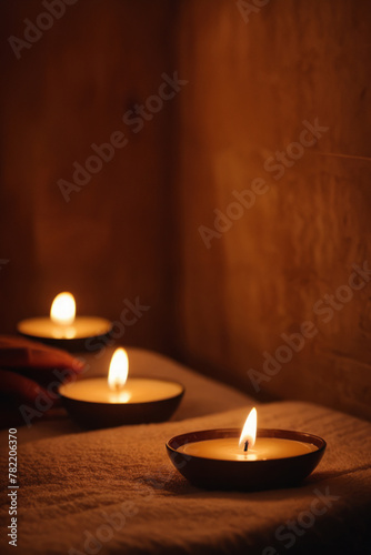 A peaceful and relaxing atmosphere with burning candles and a towel on a dark background. Relaxing evening in a cozy Thai resort. Concept of calm and harmony.