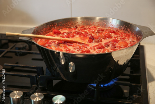 Cooking strawberry jam in a large bowl at home