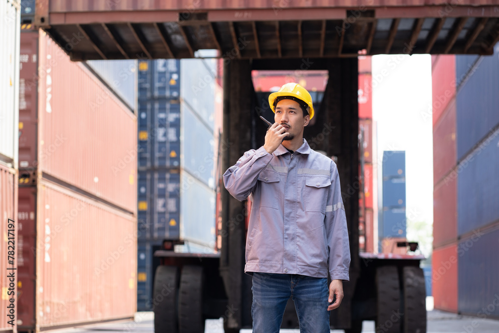 Asia logistic engineer man worker or foreman use walkie talkie direct driver forklift container at container site Asia logistic engineer man worker or foreman use walkie talkie direct driver forklift container at container site