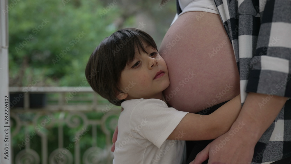 Cute little boy hugging mother's pregnant belly showcasing love and affection during late stage of pregnancy Cute little boy hugging mother's pregnant belly showcasing love and affection during late stage of pregnancy