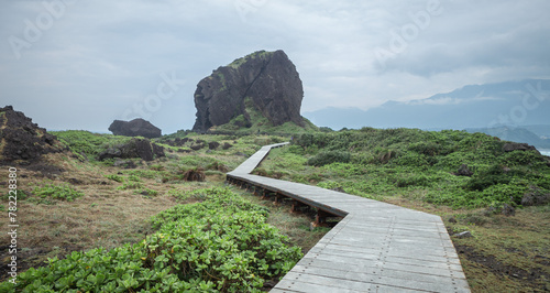 A zigzagging boardwalk extending into the distance with a rock in the end, Sanxiantai, Taiwan photo