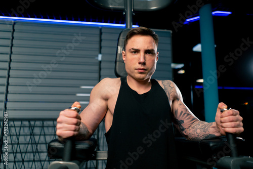 close up in the gym a young handsome guy with tattoos pumps up his abs on the horizontal bar © Guys Who Shoot