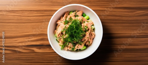 A bowl of cooked salmon and veggies on wooden surface